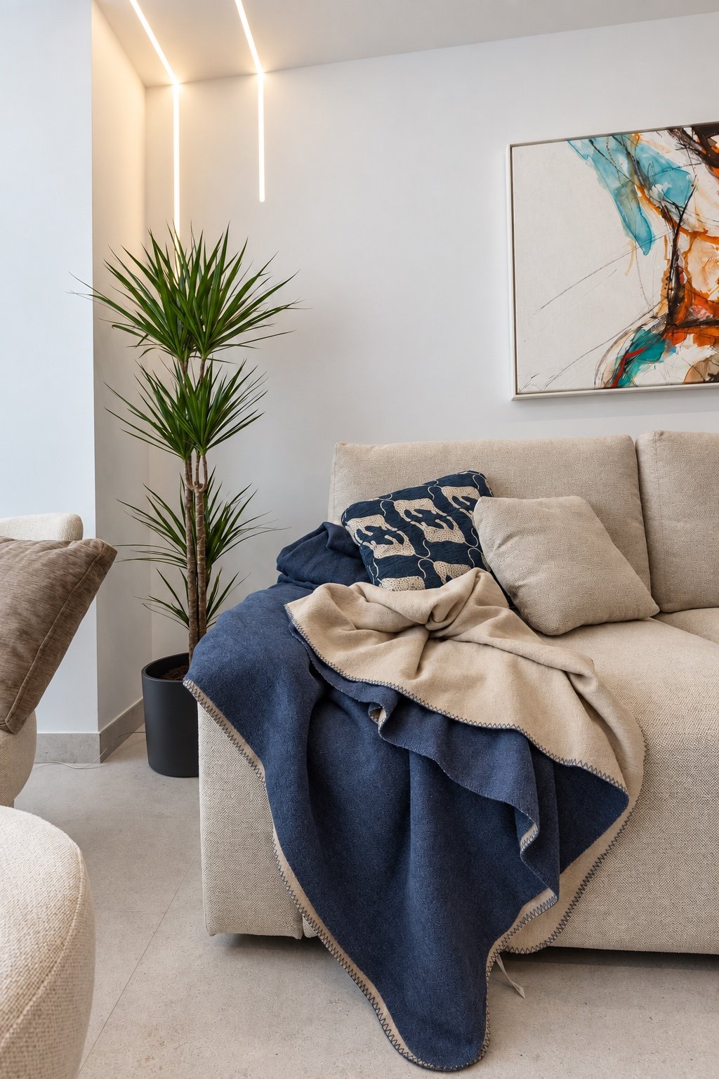Detalle de sofá con mantas y cojines azules y beige que muestran diferentes texturas