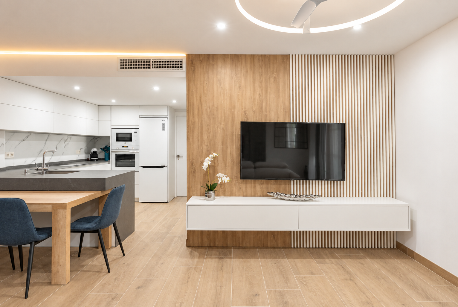 Vista frontal del mueble de televisión suspendido, panel de madera y cocina contigua
