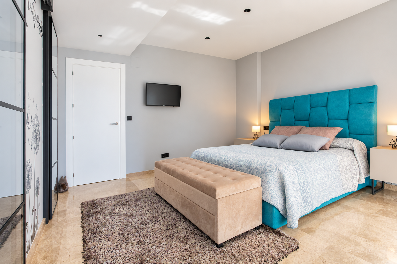 Dormitorio con cabecero turquesa, banco beige y alfombra gris